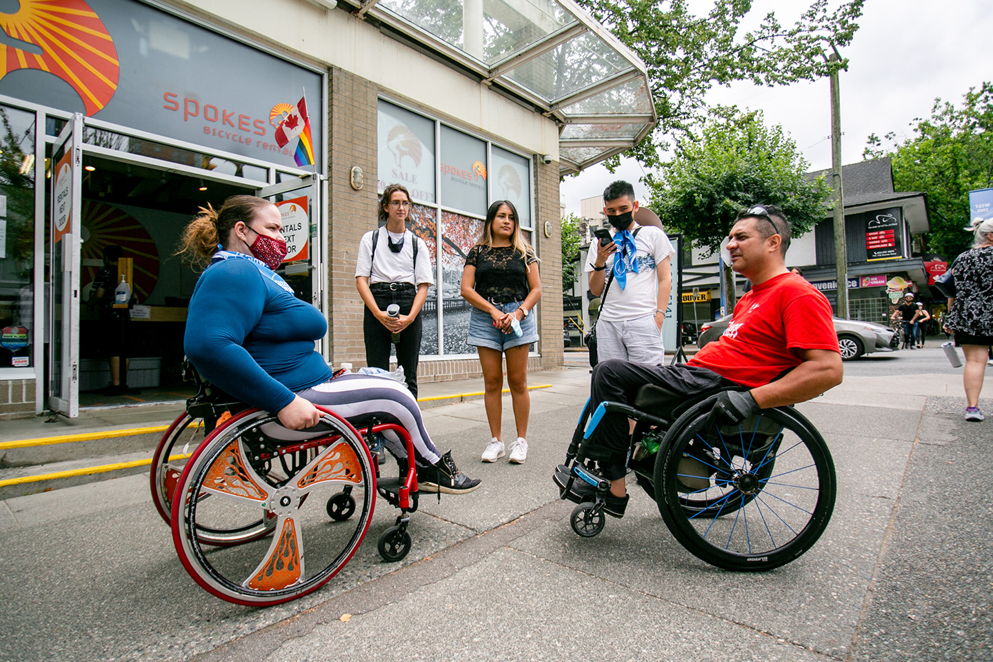 MOCA-2021-YVR---Photo-by-Alexa-Fernando---182 inter-abled gathering of 5 people on a vancouver sidewalk. two are wheelchair users