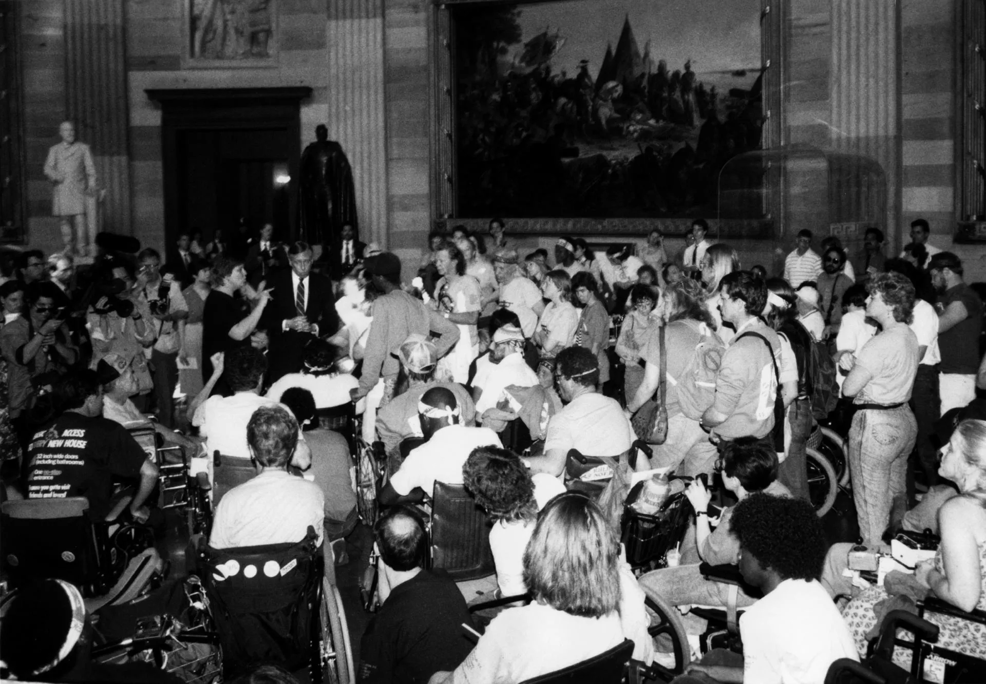 Hundreds of disability rights advocates and activists descend on the Capitol’s Hoyer Rotunda A black and white photo of hundreds of disability rights advocates and activists descend on the Capitol’s Hoyer Rotunda, chanting and pushing for the ADA signing, among them in the picture, Lillibeth Navarro, Gary Bosworth, etc.